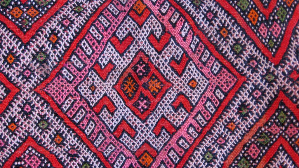Tapis amazighs colorés exposés dans un souk marocain