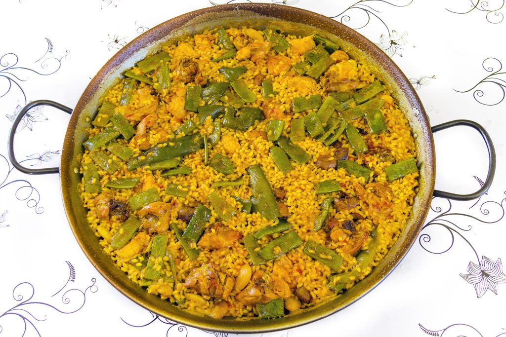 Paella valencienne servie dans un grand plat traditionnel avec du riz au safran