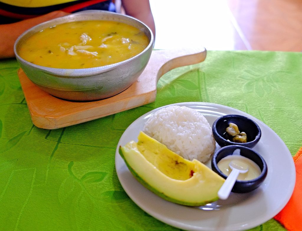 Un bol d’ajiaco santafereño servi avec son épi de maïs, sa crème et ses câpres